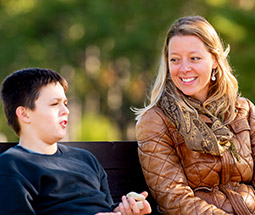 Woman talking to young boy on bench.